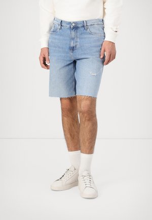 Light blue denim shorts with frayed hem, five-pocket design, and slight distressing. Worn with white sneakers and ankle socks.