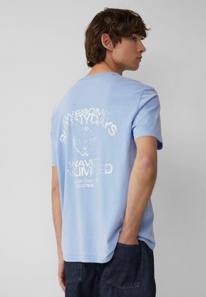 Jasnoniebieski bawełniany t-shirt z okrągłym dekoltem, z teksturowanym białym nadrukiem z tyłu, który zawiera tekst oraz wzór niedźwiedzia.