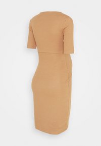 Ribbade, knälånga klänning i ljusbrunt med korta ärmar. Tätt sittande silhuett med rak skärning och minimala sömmar baktill.