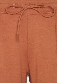 Sudaderas de color óxido con un tejido texturizado, que cuentan con una cinturilla ajustable con cordón y dos bolsillos laterales para mayor comodidad.