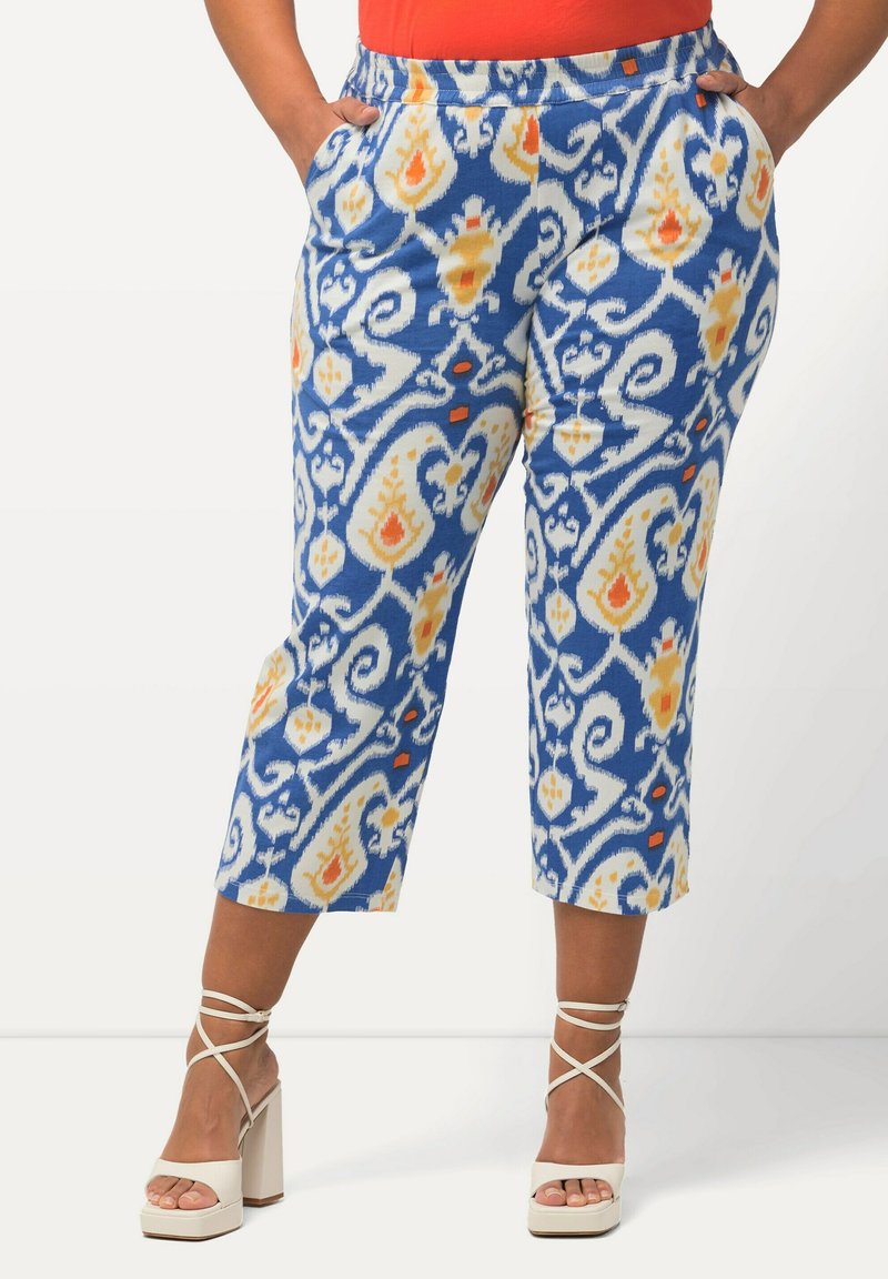 Pantalons capri à motifs bleus avec des motifs floraux blancs, jaunes et oranges. Dotés d'une taille élastique et de poches latérales.
