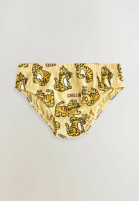 Sous-vêtements jaunes pour enfants avec des motifs répétitifs de tigres cartoon orange et le mot "CHILLIN" imprimé en rouge.