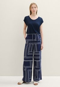Navy blue short-sleeve top paired with wide-leg pants featuring a geometric white line pattern. Soft fabric, relaxed fit, elastic waistband.