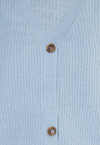 Helles blaues Strickcardigan mit V-Ausschnitt, das ein strukturiertes Muster und einen braunen Knopf auf der Vorderseite aufweist. Der Stoff sieht weich aus.