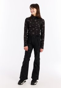 Zwarte sporttop met sterpatroon, halve rits; gecombineerd met zwarte broek met een slank ontwerp en een ritszak.