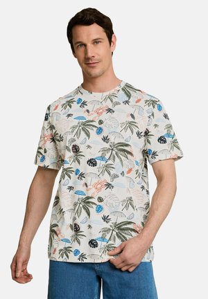 Man wearing short-sleeve white shirt with colorful tropical print including palm trees, lobsters, umbrellas, and fruit slices, paired with blue jeans.