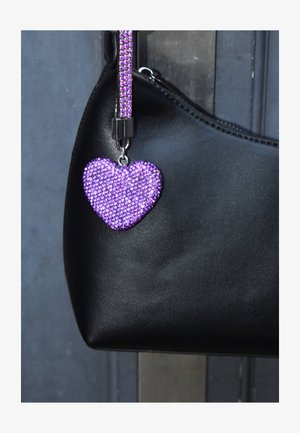 Mustast nahast käekott tekstureeritud pinnaga, mille küljes on heleroosa sädelev südamekujuline ripats helmestega rihmal.