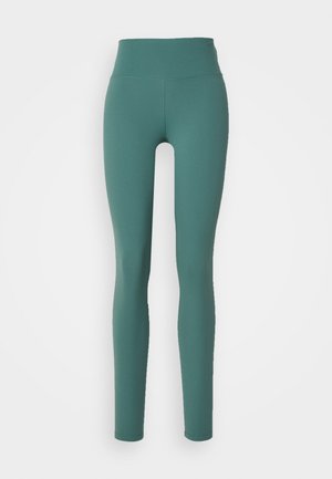 Leggings verdes de tiro alto fabricados con tejido elástico, que cuentan con una textura suave y un diseño ajustado que se extiende hasta los tobillos.