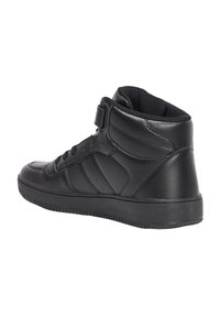 Zapatilla negra de caña alta hecha de cuero suave con punta texturizada, cuello acolchado y cinturón de velcro. Presenta costuras decorativas y suela de goma.