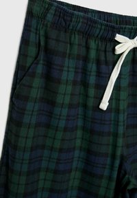 Vihreät ja laivastonsiniset ruudulliset verkkohousut, joissa on elastinen vyötärö, ja valkoinen nyöri. Ominaisuuksia ovat sivutaskut ja pehmeä, teksturoitu kangas.