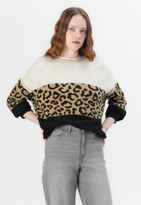Gebreide trui met een kleurblokken ontwerp in crème, beige en zwarte secties, met een luipaardprint in het midden. Zachte stoffen textuur.