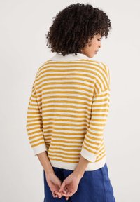 Pull rayé avec des bandes horizontales jaunes et blanches, un col blanc et des manches trois-quarts. Texture douce et design décontracté.