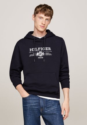 Sudadera azul marino de algodón con capucha ajustable y bolsillo frontal tipo canguro. Presenta texto blanco y un diseño gráfico en el pecho.