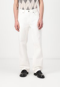 Witte denim broek met een rechte pasvorm, voorzien van vijf zakken en zichtbare stiksels. Gecombineerd met zwarte leren schoenen.