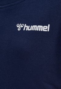 Granatowy sweter z miękką fakturą, z białym logo "hummel" i emblematem pszczoły wyszytym z przodu. Klasyczny okrągły dekolt.