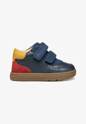 Zapatilla de cuero azul y roja con correas de Velcro, diseño perforado, suela de goma color beige y acento en el talón amarillo. Punta redondeada y cuello acolchado.