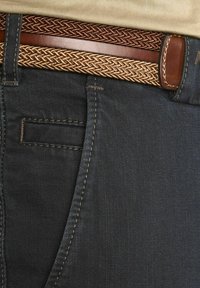 Jean noir en denim avec des coutures contrastées, accompagné d'une ceinture tressée marron avec un passepoil en cuir lisse.