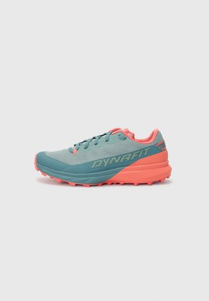 Zapatilla de trail running en teal y rosa. Presenta una parte superior de malla, suela acolchada y suela texturizada para agarre. Logo "DYNAFIT" en el lateral.