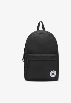 Sac à dos Converse noir avec poche zippée à l'avant et écusson rond blanc portant une étoile bleue et un texte rouge.