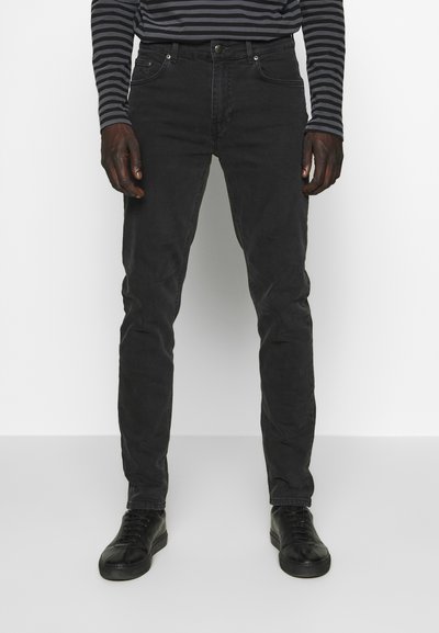Zwarte denim jeans met een slim fit, voorzien van een klassieke vijf-pocketontwerp, subtiele stiksels en een soepele textuur. Gecombineerd met zwarte sneakers.