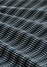 Textil cu un fundal bleumarin, având un model repetat de dungi rectangulare verzi și albe, creând un aspect texturat și stratificat.