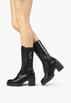 Czarne skórzane kozaki za kolano z masywnym obcasem, sznurowaniem z przodu oraz ozdobnymi bocznymi suwakami ze złotymi akcentami. Podeszwa z fakturą.