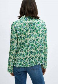 Bloemige blouse met groene en blauwe patronen op een lichte achtergrond; lichtgewicht, met lange mouwen, met een geplooide textuur en kraag.