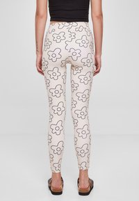 Lett rosa leggings med blomstermønster i svart kontur. Myk stoff, tettsittende passform, høy midje, og ankel-lengde design.