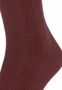 Calza bordeaux a coste che mostra la texture e il contorno, mettendo in evidenza il motivo lavorato ai bordi della caviglia e del polpaccio.