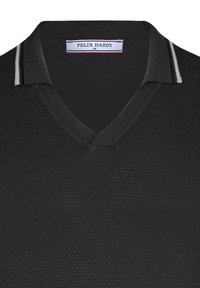Camisa polo negra con un patrón texturizado, diseño de escote en V y un cuello que presenta una estrecha franja blanca y gris. Etiqueta de la marca visible.