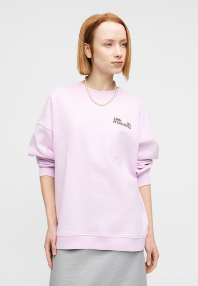 Ροζ ανοιχτόχρωμο φούτερ σε μεγάλες διαστάσεις με ριμπ μανσέτες και τελείωμα. Διαθέτει τυπωμένο λογότυπο στο αριστερό μπροστινό μέρος. Λείο ύφασμα και χαλαρή εφαρμογή.