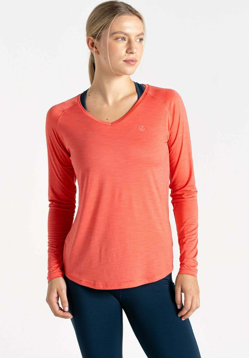 Langärmliges Sportoberteil in hellem Koralle mit V-Ausschnitt, glatter Textur und abgerundetem Saum, kombiniert mit marineblauen Leggings. Dezente Logodetails.