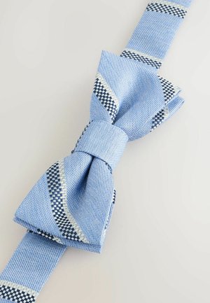 Světle modrý texturovaný motýlek s diagonálními bílými a tmavě modrými kostkovanými pruhy na jednobarevném světle pozadí.