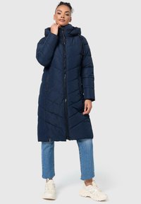 Manteau matelassé marine avec capuche, fermeture éclair avant et deux poches latérales. Il présente un design long et une finition brillante.
