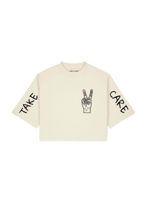 T-shirt court beige avec "TAKE" sur la manche gauche, "CARE" sur la manche droite, et une main faisant un signe de paix avec les mots amour, foi, joie, espoir et paix.
