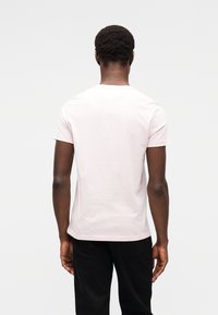 Ροζ ανοιχτόχρωμο κοντομάνικο μπλουζάκι από απαλό βαμβάκι, με κλασικό στρογγυλό λαιμόκοψη και άνετη εφαρμογή, εμφανιζόμενο από πίσω.