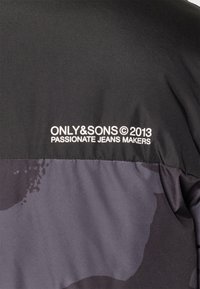 Giacca nera e grigia con una superficie liscia. Presenta sul retro il testo di branding bianco "ONLY&SONS © 2013 PASSIONATE JEANS MAKERS".