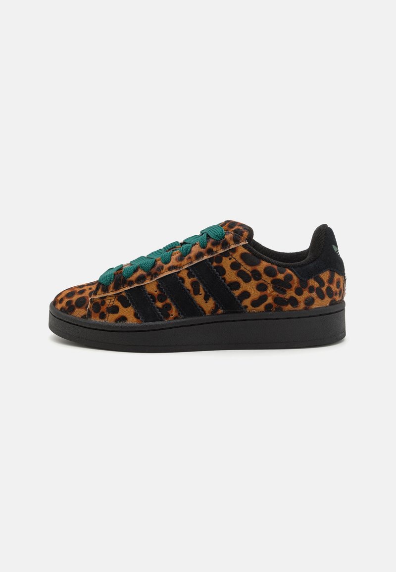 Sneakers med leopardmönster och en texturerad överdel i orange och svart, gröna snören och svarta ränder. Har en platt svart sula.