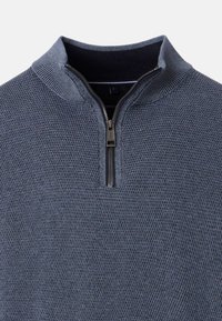Quarter-zip tröja i texturerad marinblå trikå; har en ståkrage och en metalldragkedja med ett svart draghandtag.