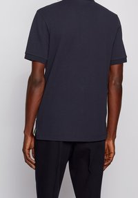 Námořnický polo tričko s texturovanou tkaninou, krátkými rukávy a plochým límečkem. Má rovný lem a malou boční cedulku s logem.