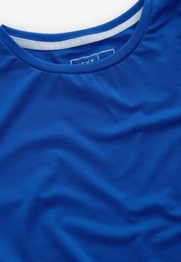 Sinine spordipäevitussärk, millel on ümmargune kaelus ja tekstureeritud kangas. Särgil on sile viimistlus ja see on peamiselt ühesuguse värvusega.