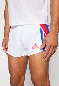 Balti sporta šorti ar sarkaniem un ziliem akcentiem, ar Apvienotās Karalistes karoga iedvesmota dizaina, izgatavoti no viegla auduma. Iekļauta Adidas logo.