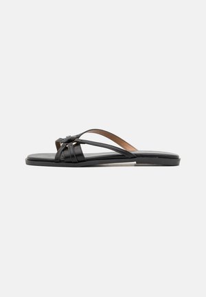 Black leather flip-flop sandals with thin, crisscrossing straps and a flat sole, featuring a minimalist design and smooth texture.