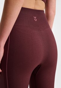Burgundowe legginsy z wysokim stanem o fakturze prążkowanej, z małym logo i detalem szwu wzdłuż boku dla dodatkowego stylu.
