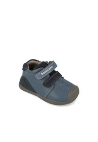 Zapato infantil de cuero azul con una suela de goma gris, que cuenta con una correa de velcro, detalles de costura y un gráfico de animal en el costado.