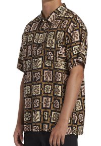 Camisa de manga corta con un patrón floral en marrón, negro y beige sobre un fondo claro, con cierre de botones y un corte relajado.