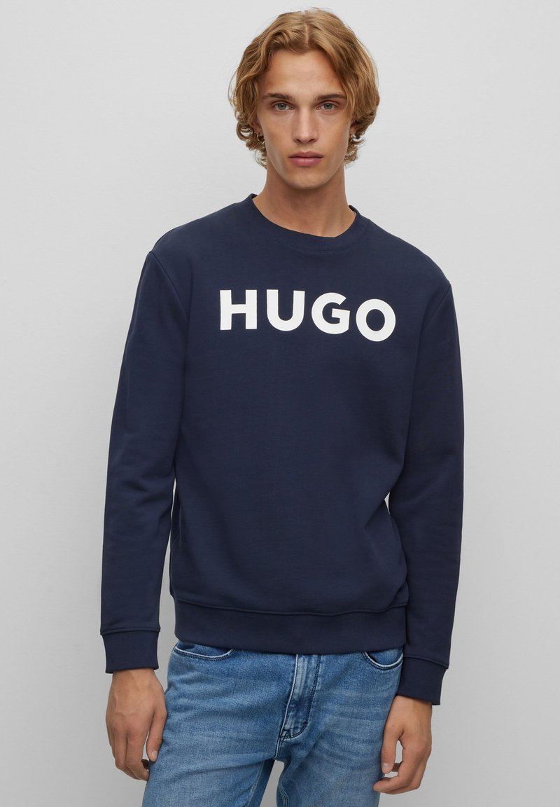 Felpa blu navy in cotone, caratterizzata da un audace logo bianco "HUGO" sulla parte anteriore, con maniche lunghe e polsini e orlo a costine.