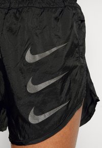 Černé šortky Nike z lehké strukturované tkaniny. Na boku mají tři stříbrná loga Nike Swoosh a elastický pas.