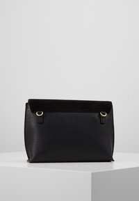 Černá kožená taška s texturovaným povrchem a měkkým semišovým klopou. Obsahuje zlaté kovové detaily a má strukturovaný, úhlový design.