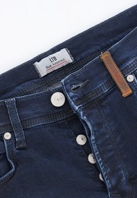 Vaqueros de mezclilla azul oscuro con una textura suave, que presentan un cierre de botones, acentos cosidos y una etiqueta "Blue Addicted" de LTB.